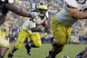 Michigan quarterback Denard Robinson, center, follows the block of teammate Stephen Schilling on his way to scoring the game-winning touchdown in the final minute against Notre Dame in an NCAA college football game in South Bend, Ind., Saturday, Sept. 11, 2010. Michigan defeated Notre Dame 28-24. (AP Photo/Michael Conroy)